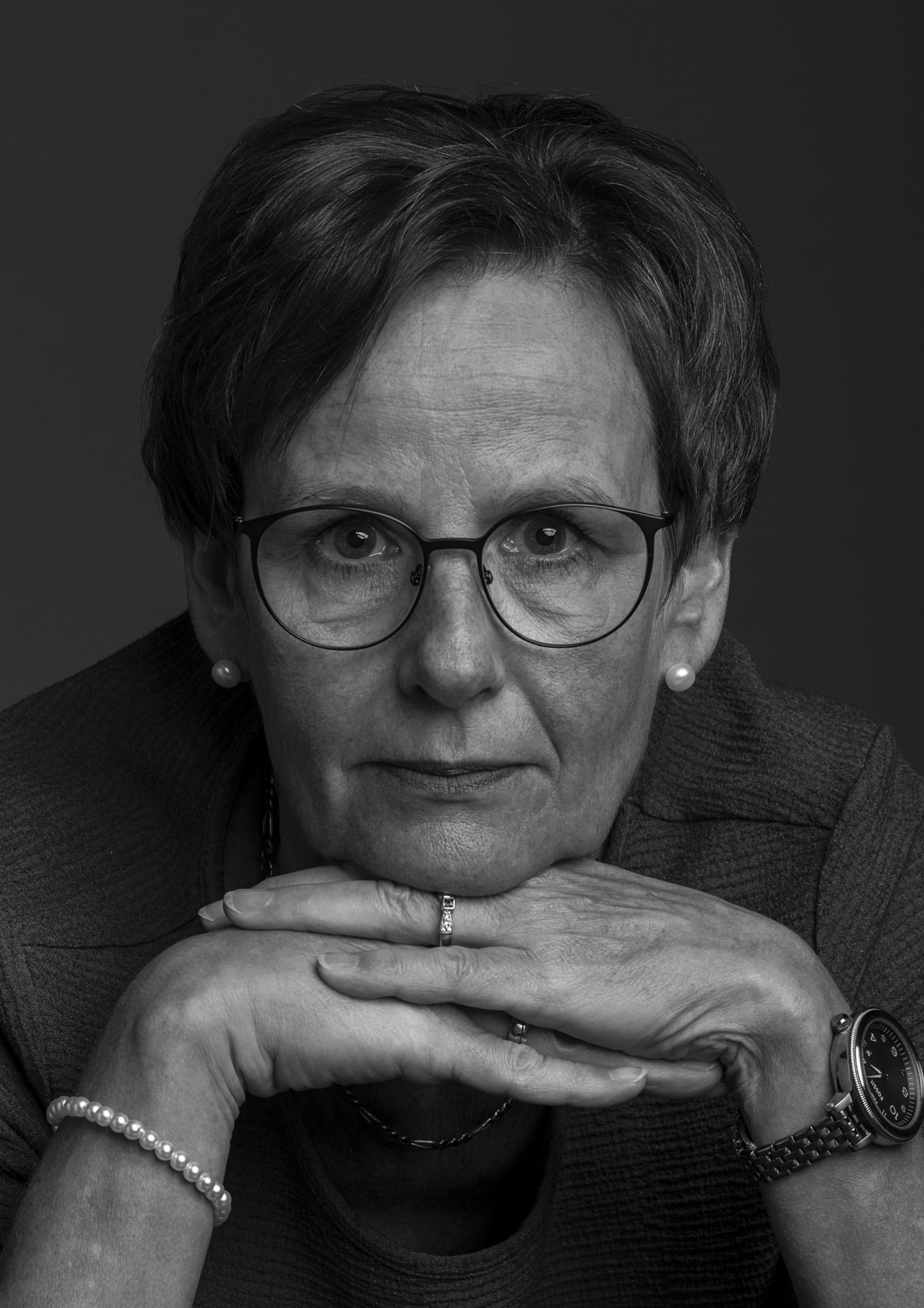 Frau mit Brille auf Händen gestützt